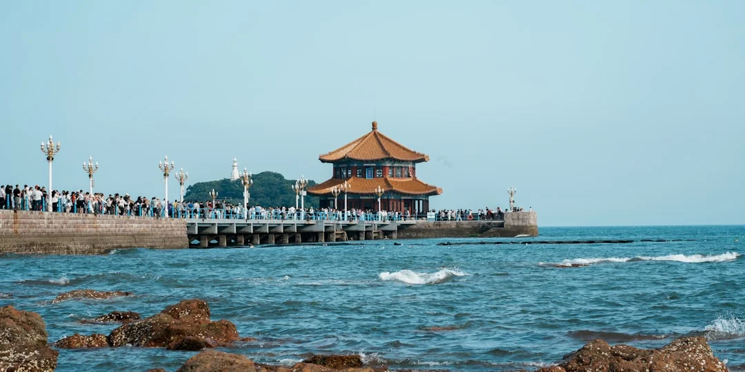 a group of people standing on a pier next to the ocean